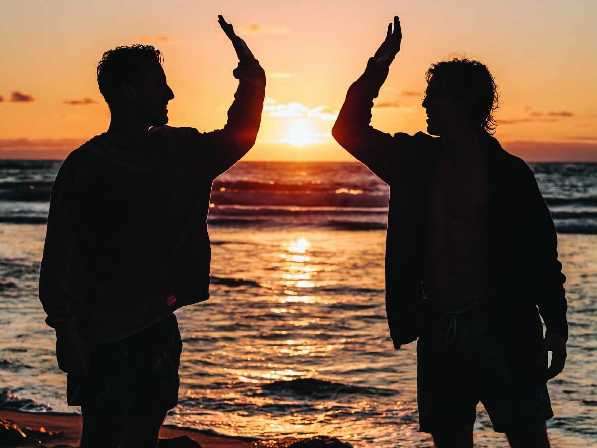 Two people at beach hitting hands